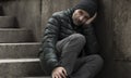 Dark and edgy urban portrait of middle aged sad and depressed unemployed man sitting outdoors on dirty street corner staircase