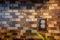 Dark electrical outlet against a tiled kitchen back splash with plastic inserts to prevent a child or baby from getting shocked