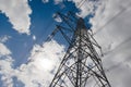 Dark Electrical transmission tower against a bright blue cloudy sly Royalty Free Stock Photo