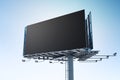 Dark empty billboard on a steel structure with a clear sky background, ideal for large scale mockups. Royalty Free Stock Photo