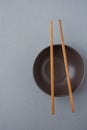 Dark Empty Bowl with Brown Bamboo Chopsticks on Grey Background. Japanese Chinese Asian Cuisine. Royalty Free Stock Photo