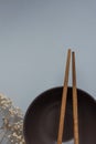 Dark Empty Bowl with Brown Bamboo Chopsticks on Grey Background Twig of Dry Small White Flowers. Japanese Chinese Asian Cuisine Royalty Free Stock Photo