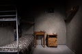 Dark empty jail cell with iron bunk bed and bedside table