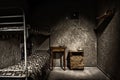 Dark empty jail cell with iron bunk bed and wooden bedside table
