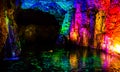 A dark enchanting colourful underground cave with waterfall and dark flashes of sizzling light