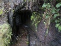 Dark entrance to the tunnel of water duct levada at hiking trail Casa del Monte to Los Tilos at mysterious laurel forest Royalty Free Stock Photo