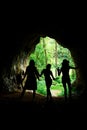 Dark female silhouettes at the entrance to natural cave .