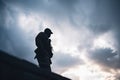 dark figure silhouetted against a stormy sky