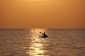 Dark figure of sportsman rowing alone on his kayak boat on sea water at sunset. Active extreme sports concept Royalty Free Stock Photo