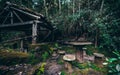 Dark forsaken draw-well in rainforest with table and stools near