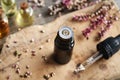 A dark glass bottle of essential oil with a dropper and flowers Royalty Free Stock Photo