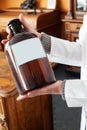 large dark glass bottle in hands of woman in white coat