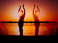 Dark glowing silhouettes of slim woman dancing traditional tribal belly dance in front of red sky