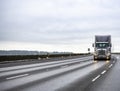 Dark gray big rig semi truck tractor transporting cargo in semi trailer driving on the wide highway road at the twilight time Royalty Free Stock Photo