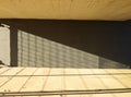 Dark gray concrete block wall of a tunnel. Rough concrete on the ceiling and on the pavement with side light and shadow of a gate. Royalty Free Stock Photo