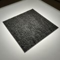 Dark gray felt square centered on a smooth, illuminated surface Royalty Free Stock Photo