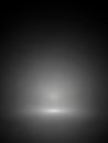 A dark gray gradient background with a bright white light emanating from the bottom center creating a spotlight effect on a smooth Royalty Free Stock Photo