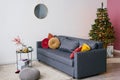 Dark gray sofa with bright red and yellow pillows, Christmas tree in the interior of the living room Royalty Free Stock Photo