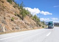 Dark green big rig semi truck with high cab roof transporting cargo in semi trailer running on the winding mountain road at sunny Royalty Free Stock Photo