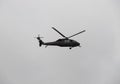 A dark green black Hawk police helicopter flying over crow during colombian independence military parade day