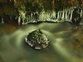 Dark green cold water of mountain stream in winter time, small icicles. Royalty Free Stock Photo