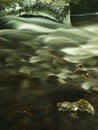 Dark green cold water of mountain stream in winter time, small icicles are hanging Royalty Free Stock Photo