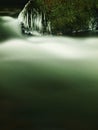 Dark green cold water of mountain stream in winter time, small icicles. Royalty Free Stock Photo