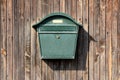 Dark green metal vintage retro mailbox with lock mounted on wooden boards barn wall