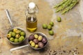 Dark and green olives in two metal bowls. Olive oil bottle