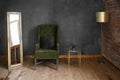 Dark green soft armchair near plaster wall