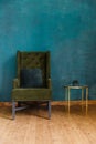 Dark green soft armchair near plaster wall.