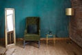 Dark green soft armchair near plaster wall.