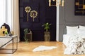 Dark grey bedroom interior with fur rug, gold accessories, simple painting and window with curtains in the real photo