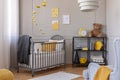 Dark grey blanket on wooden crib in yellow