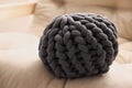 Dark grey chunky knitted pillow on beige sofa, closeup Royalty Free Stock Photo