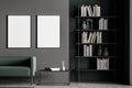 Dark grey modern living room interior furnished by green sofa, coffee table, bookshelf and two blank posters on black wall. Royalty Free Stock Photo