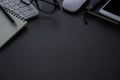 Dark grey office desk table with keyboard, notebook and glasses, mouse with equipment other office supplies. Royalty Free Stock Photo