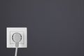 Dark wall with power socket and inserted plug, space for text. Electrical supply Royalty Free Stock Photo