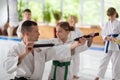 Dark-haired aikido trainer helping girl to use nunchucks