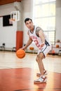 Dark-haired athletic man playing basket-ball in the gym