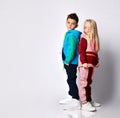 Dark haired boy and blonde girl in stylish jym suits standing back to back. Portrait isolated on light grey, copy space Royalty Free Stock Photo