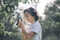 Dark-haired boy cutting branches in the garden and looking involved