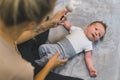 Dark-haired caucasian infant baby boy in a onesie in shades of gray clenching his fists and being distracted by a bunny Royalty Free Stock Photo