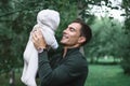 Dark-haired dad in green jacket with infant baby in hands, happy fatherhood, unconditional love Royalty Free Stock Photo