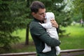 Dark haired dad in green jacket kisses his infant baby in hands, happy fatherhood, unconditional love Royalty Free Stock Photo