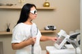Dark-haired dermatologist operates laser hair removal machine Royalty Free Stock Photo