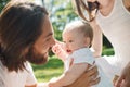 Dark-haired father is gently holding in the arms his little charming daughter and watching into her eyes on a summer day