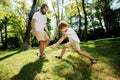 Dark-haired father and his little son dressed in the white t-shirts are playing football on a lawn on a warm day. Royalty Free Stock Photo