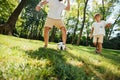 Dark-haired father and his little son dressed in the white t-shirts are playing football on a lawn on a warm day. Royalty Free Stock Photo