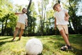 Dark-haired father and his little son dressed in the white t-shirts are playing football on a lawn on a warm day. Royalty Free Stock Photo